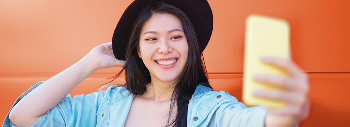Mujer Joven Sonriente y con Sombrero Tomndose un Selfie
