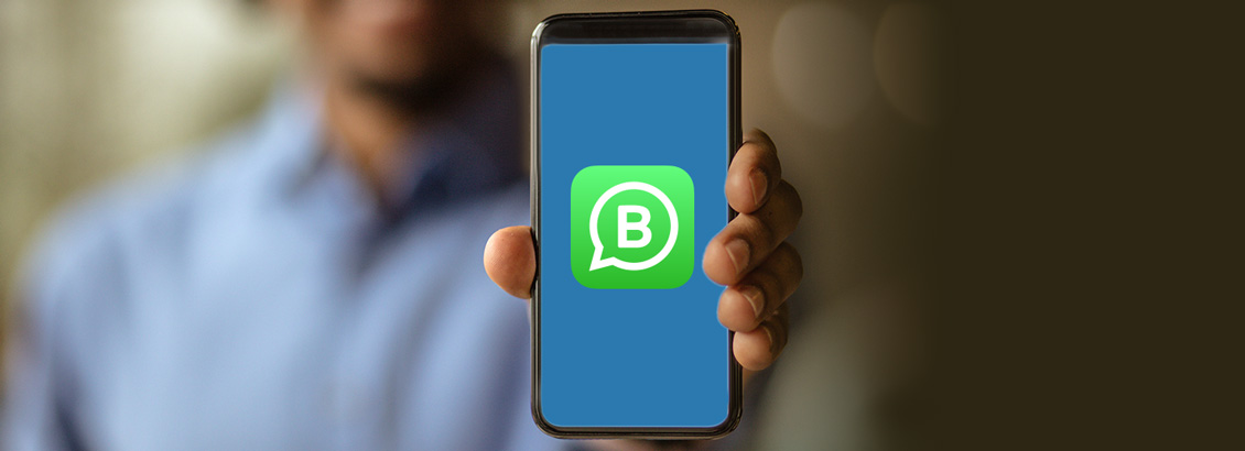 Dueo de Negocio Sosteniendo Smartphone con Logo de WhatsApp Business Dentro
