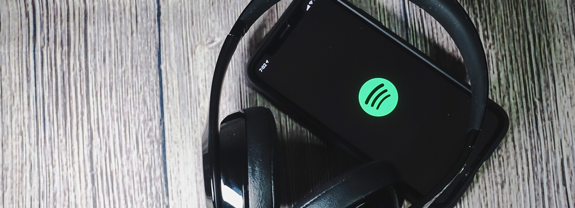 Audfonos Encima de Smartphone con el Logo de Spotify en la Pantalla
