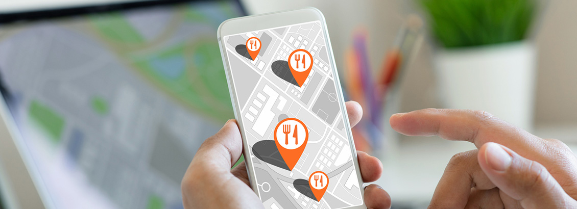 Manos Sosteniendo Smartphone con Mapa Digital e Iconos de Restaurantes que Muestran su Ubicacin