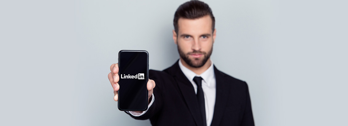 Empresario Mostrando Smartphone a la Cmara con Logo de LinkedIn en Pantalla