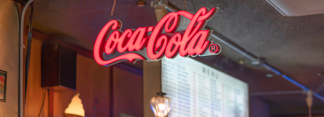 Logo Luminoso de Coca-Cola Dentro de Local Comercial como Parte de Estrategia de Marketing